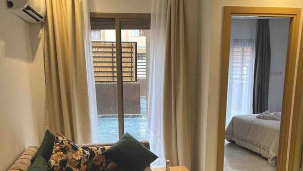 Ein modernes Hotelzimmer mit einer Sitzecke, einem kleinen Tisch und Blick ins Freie.