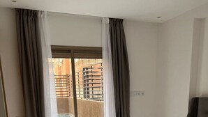 Ein Hotelzimmer mit einem Bett, einem Nachttisch und Blick auf einen Pool und Außenbereich durch große Fenster.