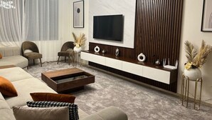 Una sala de estar moderna con un sofá, una mesa de centro, un televisor y elementos decorativos.