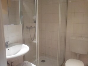A bathroom with a glass-enclosed shower, a white sink, and a toilet. - Landhaus Wachendorf (Bruchhausen-Vilsen)