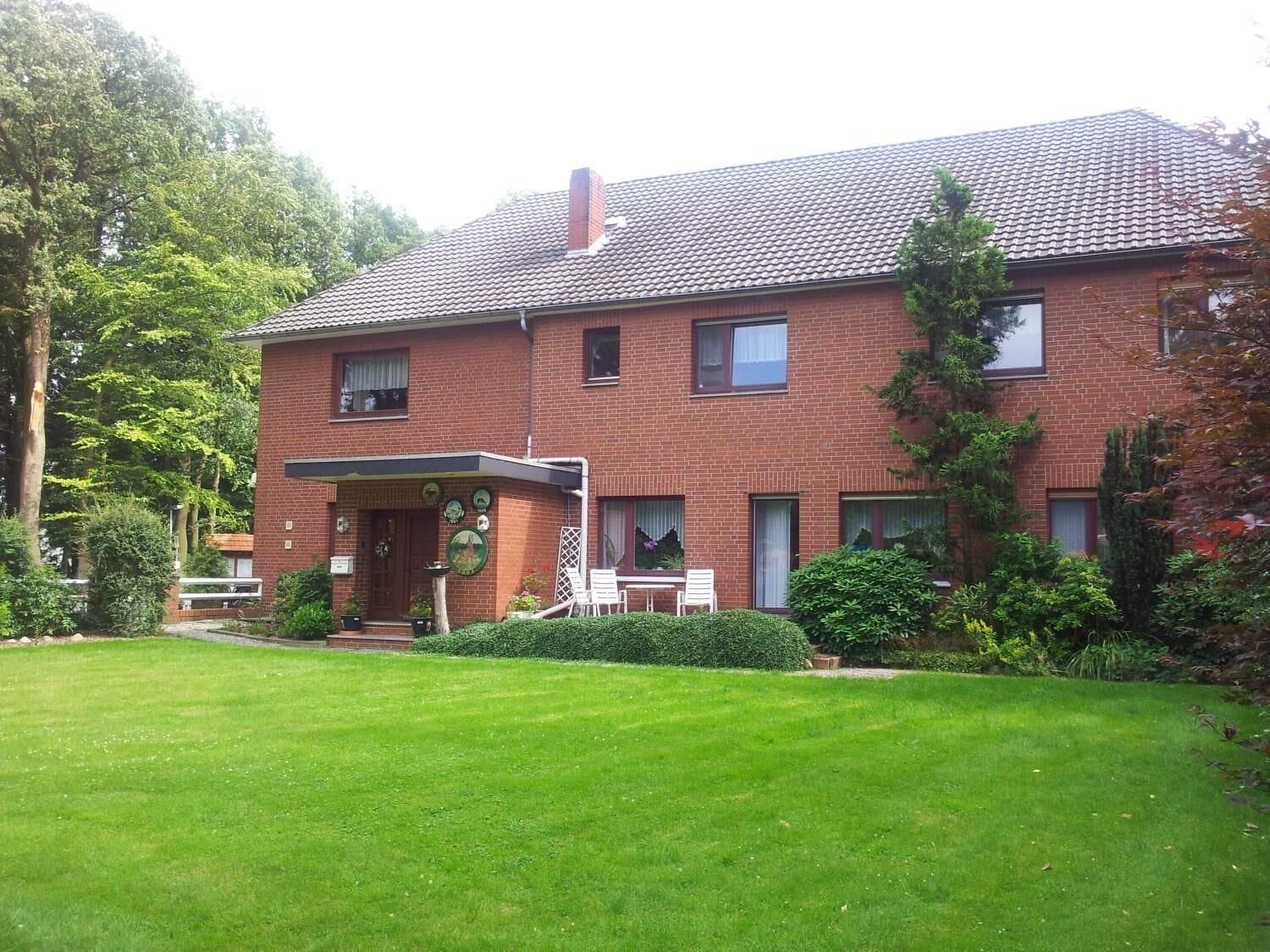 A two-story brick house with a tiled roof, a front porch, and a well-maintained lawn.