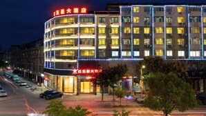 Een hotel met meerdere verdiepingen, verlichte signage en een moderne gevel.