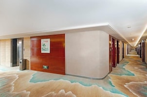 Un couloir d’hôtel avec un tapis à motifs, un comptoir de réception et une enseigne indiquant le nom de l’hôtel.