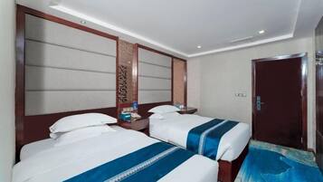 Una habitación de hotel con dos camas, cabecero de madera, mesita de noche y una puerta.