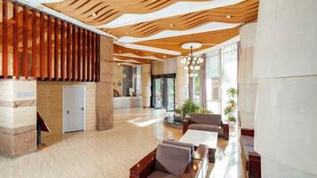 A spacious lobby with a modern wooden ceiling, a reception desk, and seating areas.