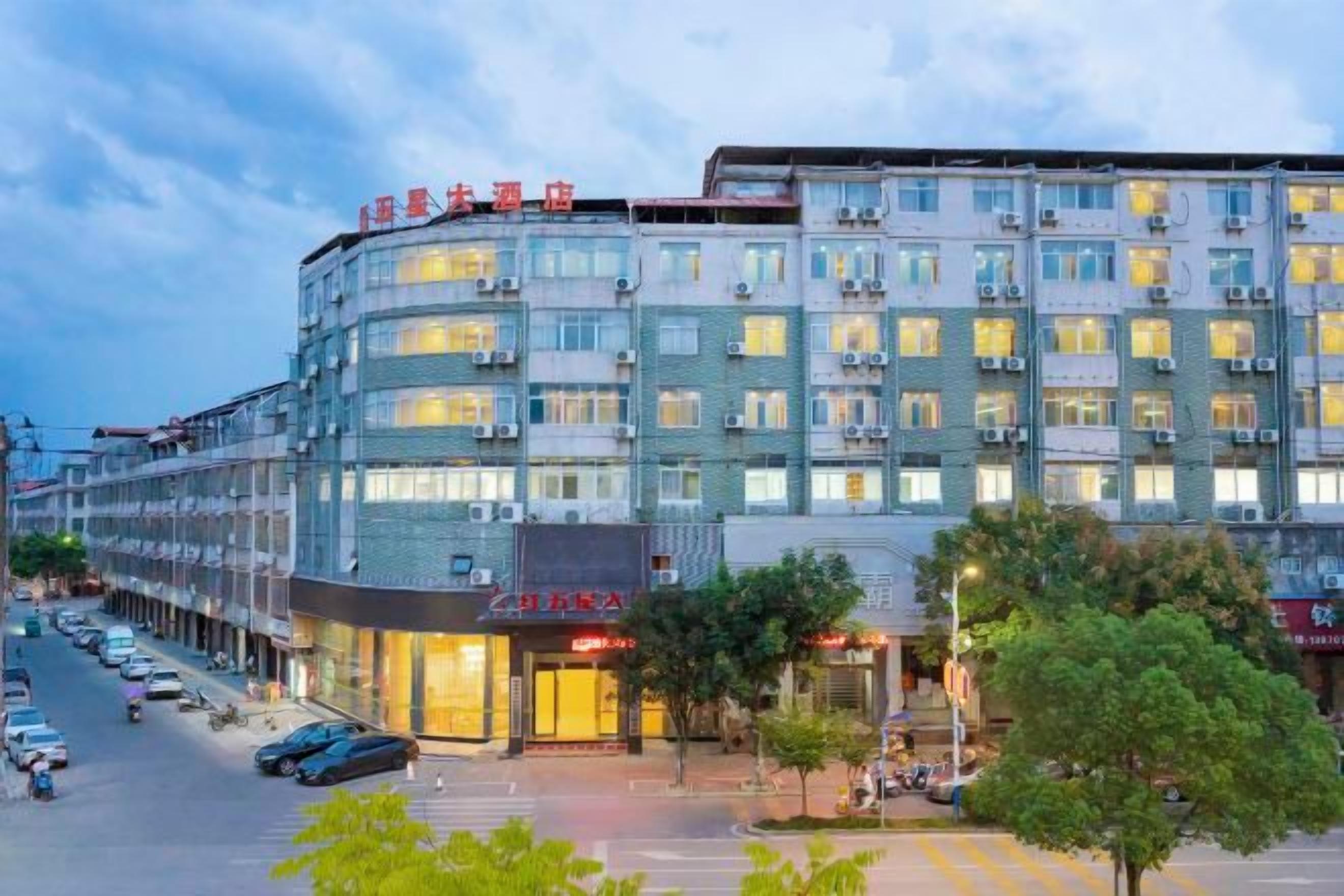 Un hotel de varios pisos con fachada moderna, múltiples balcones y entrada a nivel de calle con señalización.