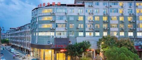 Un hotel de varios pisos con fachada moderna, múltiples balcones y entrada a nivel de calle con señalización.