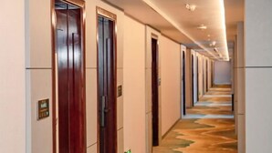 Een hotelgang met houten deuren, een kamerbreed tapijt met patroon en een lange gang.