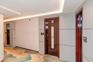 Un pasillo de hotel con una puerta de madera, un letrero en la pared y una alfombra con un diseño de olas.