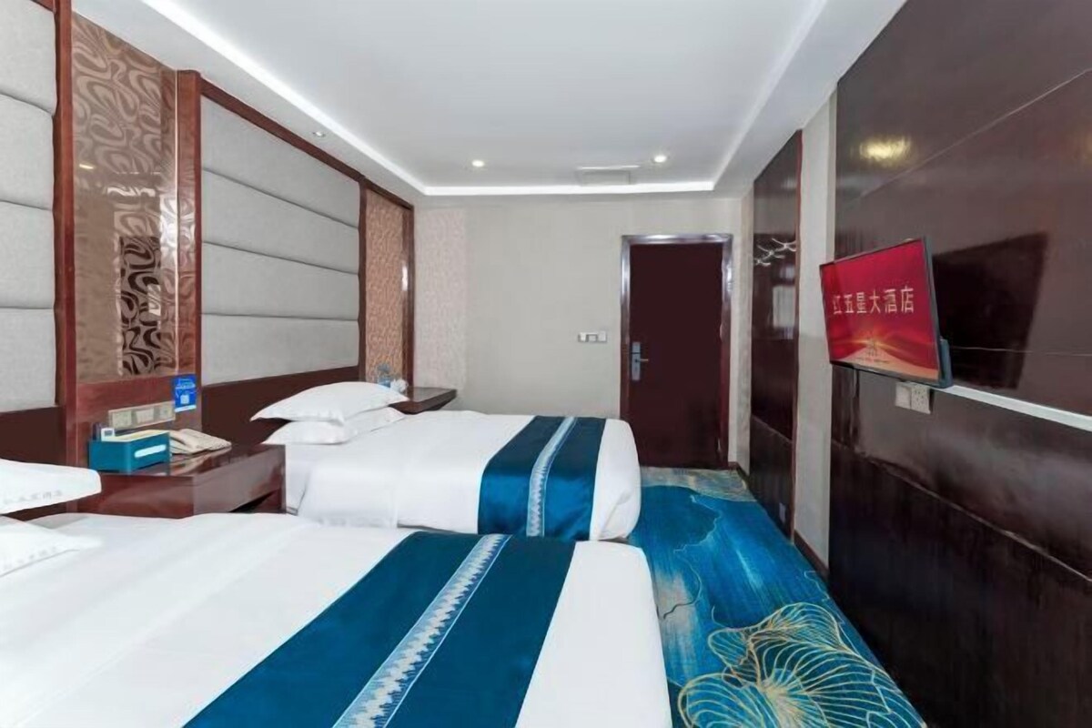 A hotel room with a bed, bedside table, and a TV on the wall.