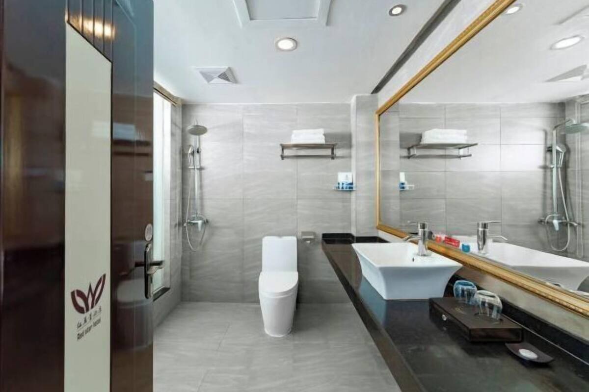 Une salle de bain moderne avec un grand miroir, une baignoire, des toilettes et un meuble-lavabo.