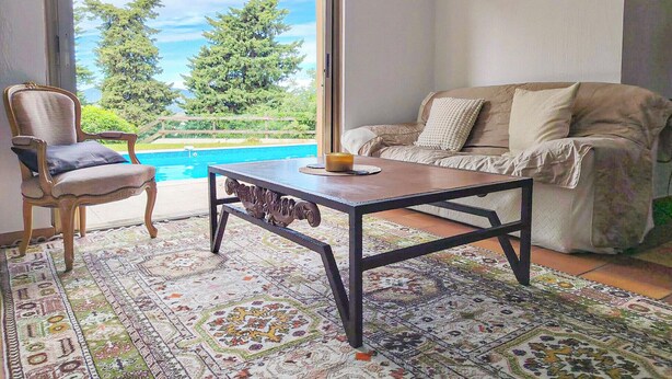 A room with a pool view, a sofa, a chair, and a patterned rug.