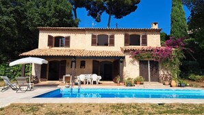 A two-story building with a swimming pool, outdoor seating, and a garden.