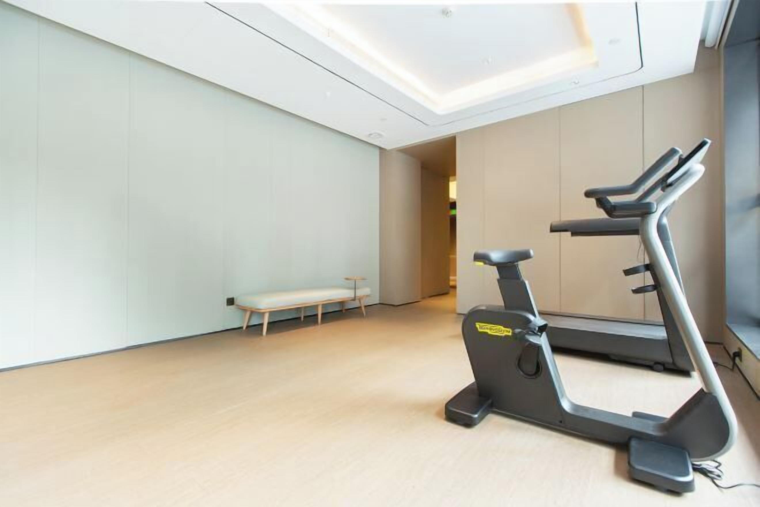 Une salle de sport moderne équipée d’un tapis de course et d’un banc de musculation.