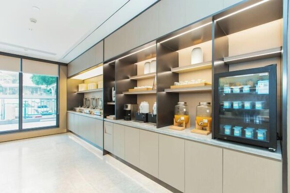 A modern kitchen with built-in appliances, a coffee machine, and a refrigerator with a glass door displaying food items.