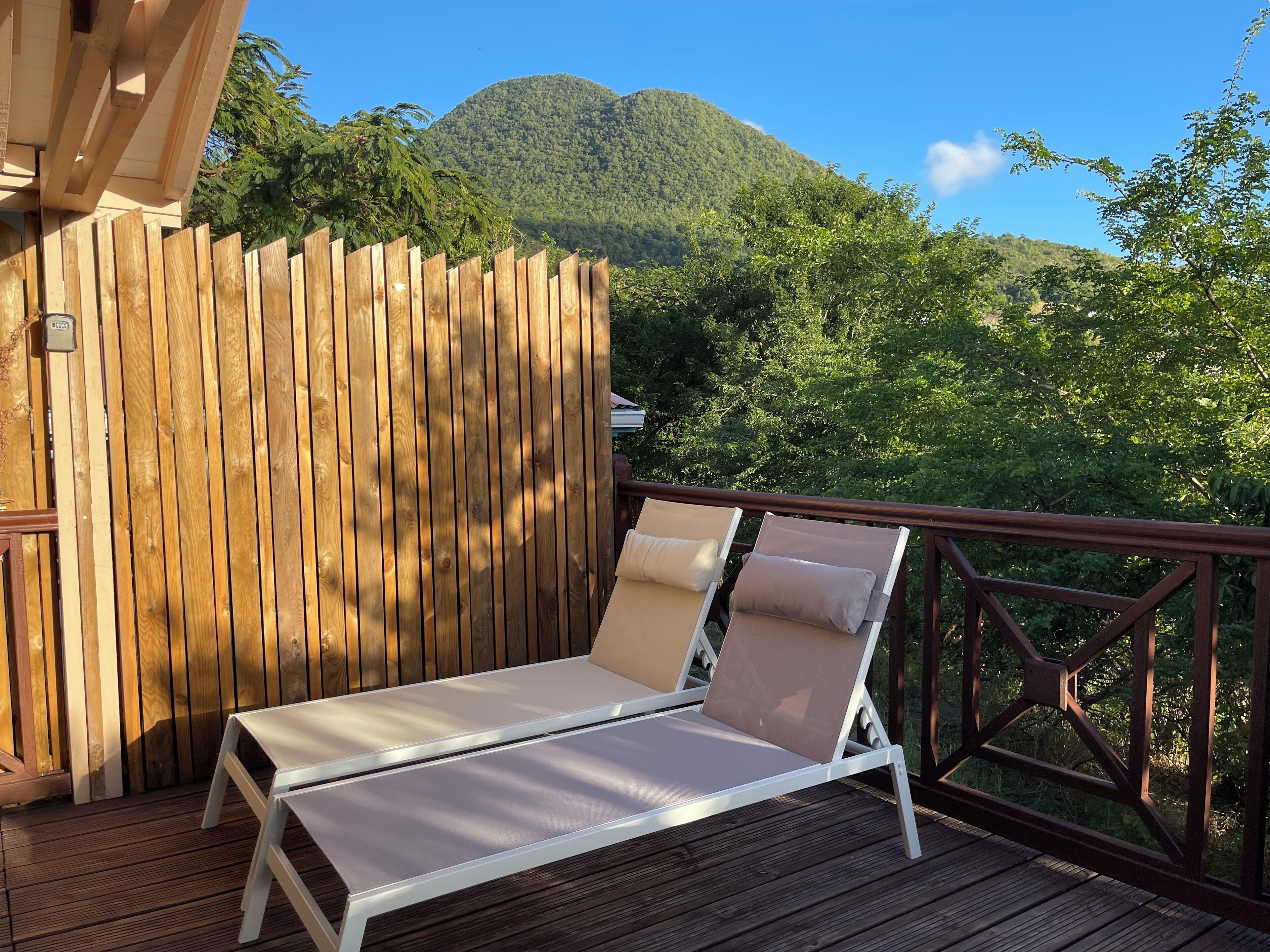 Une terrasse en bois avec deux chaises longues blanches et une clôture en bois.
