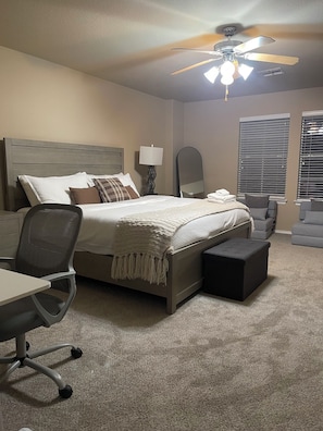 A bedroom with a bed, desk, chair, and a ceiling fan.