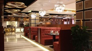 Un intérieur moderne avec des banquettes rouges, un bar et des luminaires circulaires au plafond.
