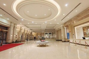A spacious hotel lobby with a central round table, a red carpet, and a reception desk. - Xiqiao Mountain Qiaoyue Resort Hotel (Foshan)