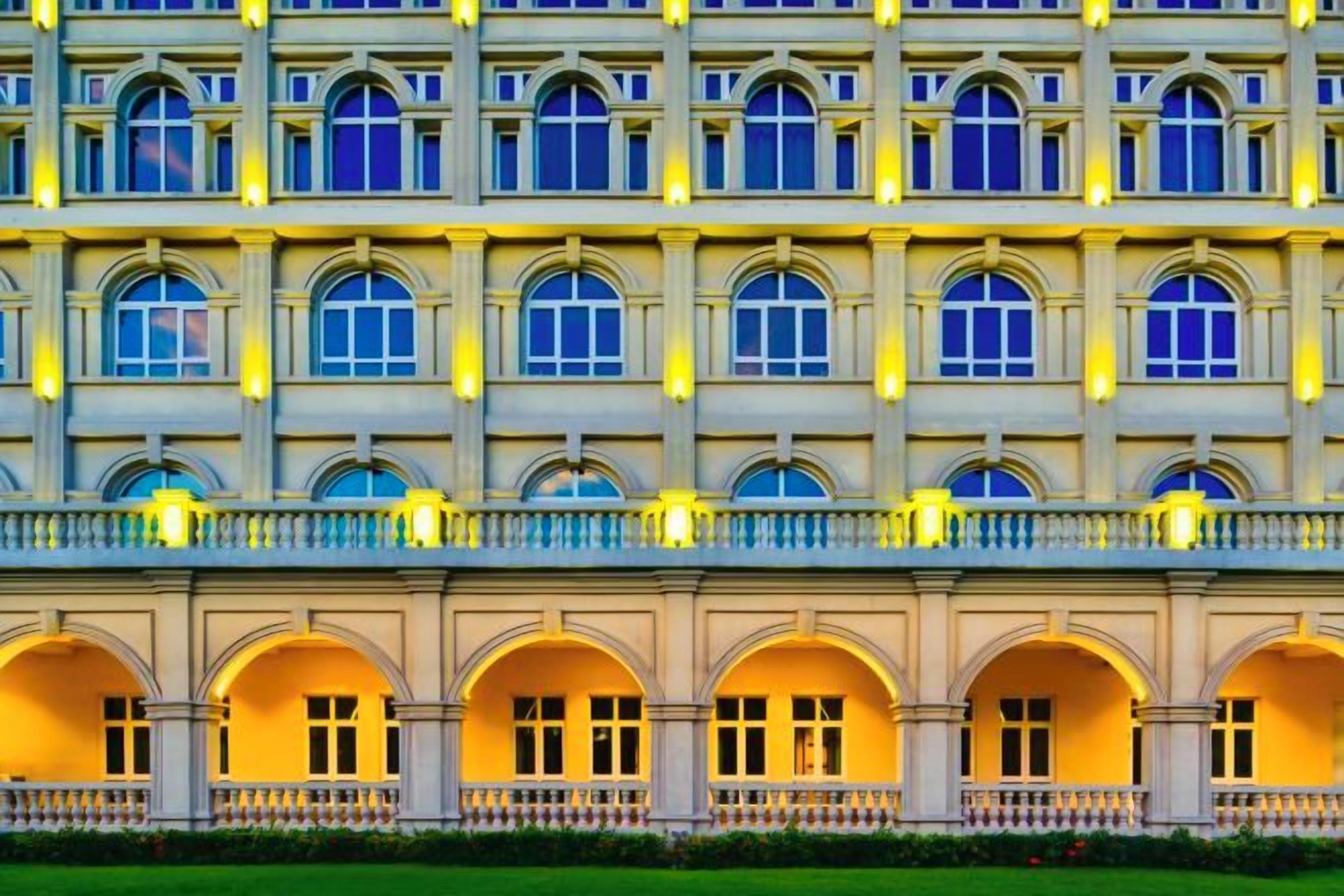 Ein mehrstöckiges Hotel mit einer symmetrischen Fassade, das eine Reihe von Bogenfenstern und Balkonen zeigt.