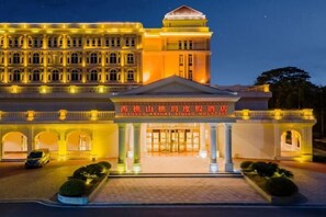 Un grand hôtel illuminé, doté d’une entrée imposante, de nombreux balcons et d’une enseigne bien visible.