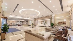 Un vestíbulo amplio con una zona de estar central, un mostrador de recepción y una escalera que conduce a los pisos superiores.