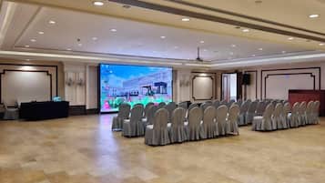 A conference room with a stage, chairs, and a large screen.