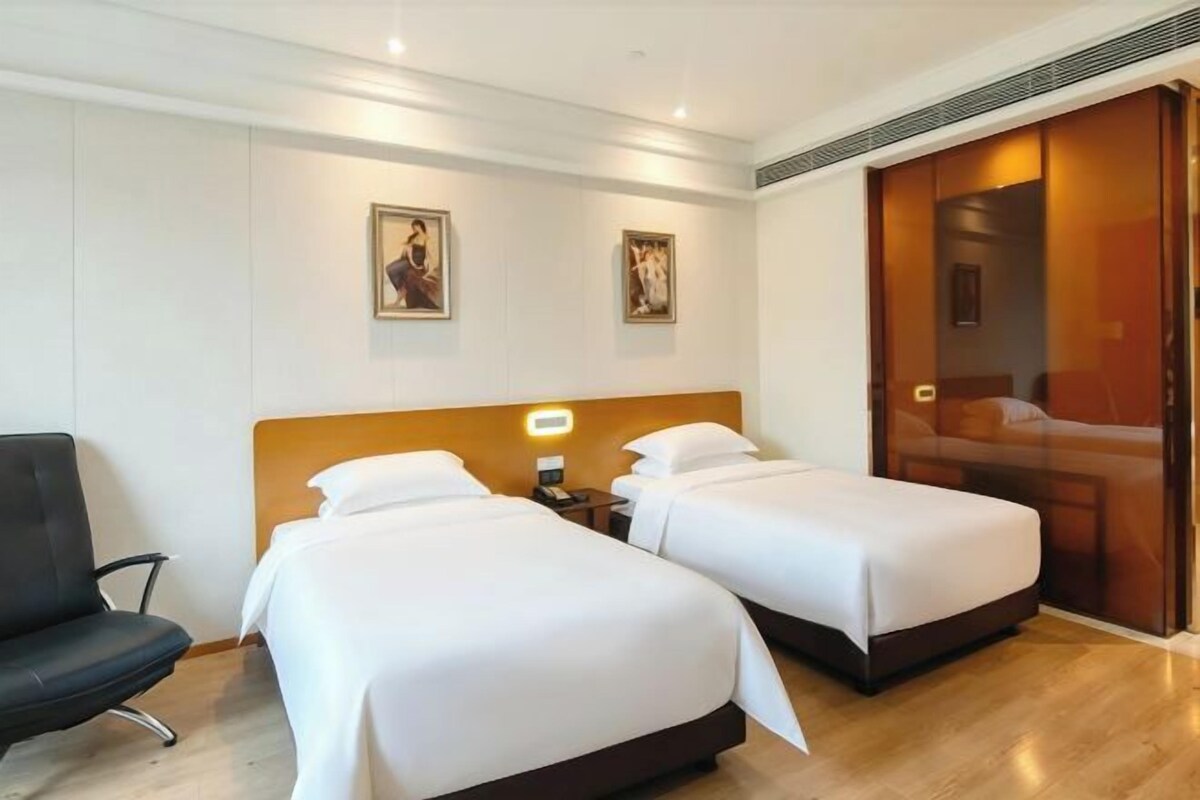 Habitación de hotel con dos camas, una silla y armario corredero.