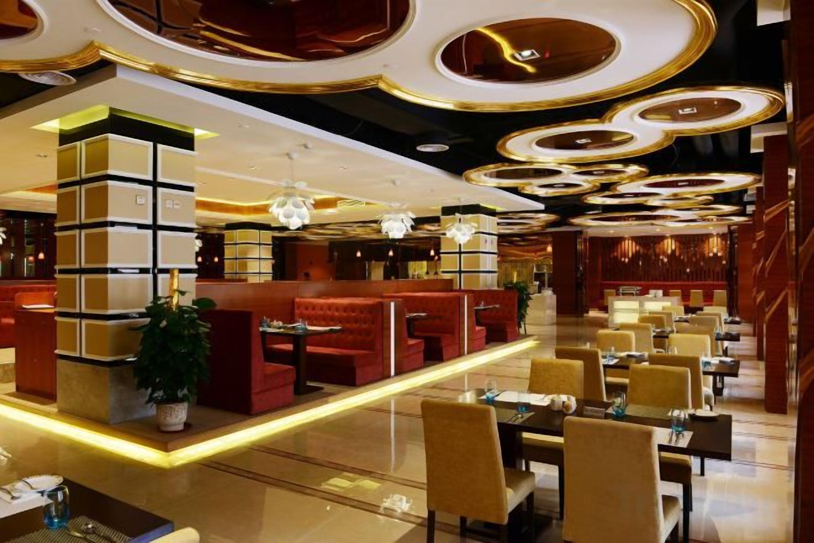 A hotel lobby with seating areas, tables, and a modern ceiling design.