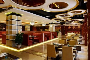 Un hall d’hôtel doté d’espaces aménagés avec des sièges, des tables et un design moderne au niveau du plafond.
