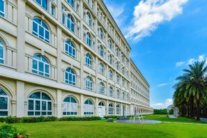 Un grand immeuble à étages, doté d’une façade symétrique, de fenêtres en arc de cercle et d’une pelouse bien entretenue.