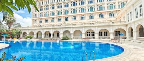 A hotel with a large central pool, multiple balconies, and a classical architectural style.