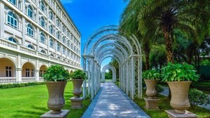 Un sendero bordeado por macetas grandes y un edificio con ventanas arqueadas.