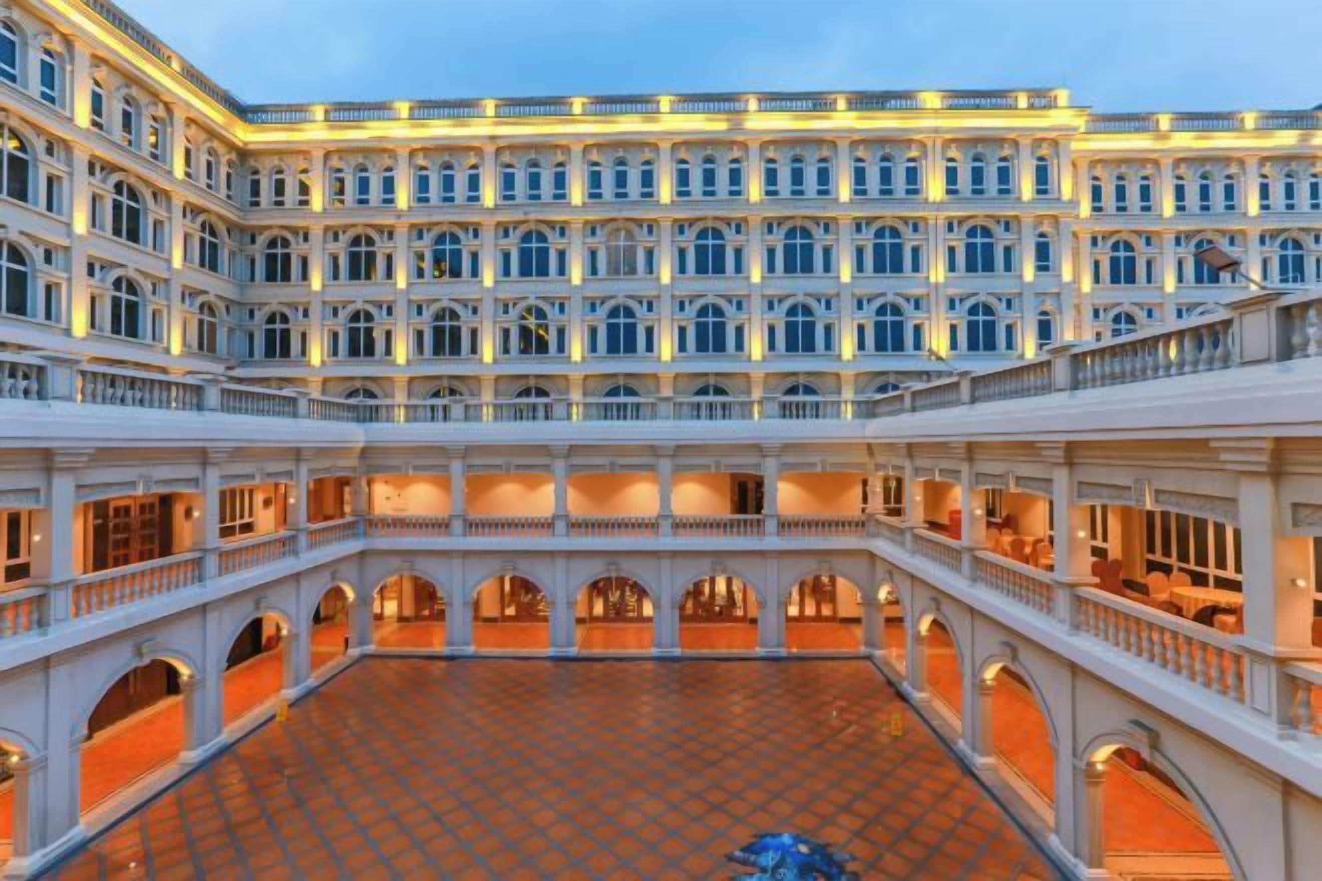 A large, multi-level hotel with a central courtyard, multiple balconies, and a grand architectural design.