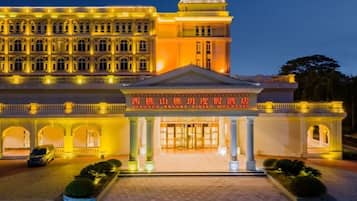 A hotel with a grand entrance, multiple arches, and a well-lit facade.