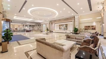 A spacious lobby with a reception desk, seating area, and a large plant.