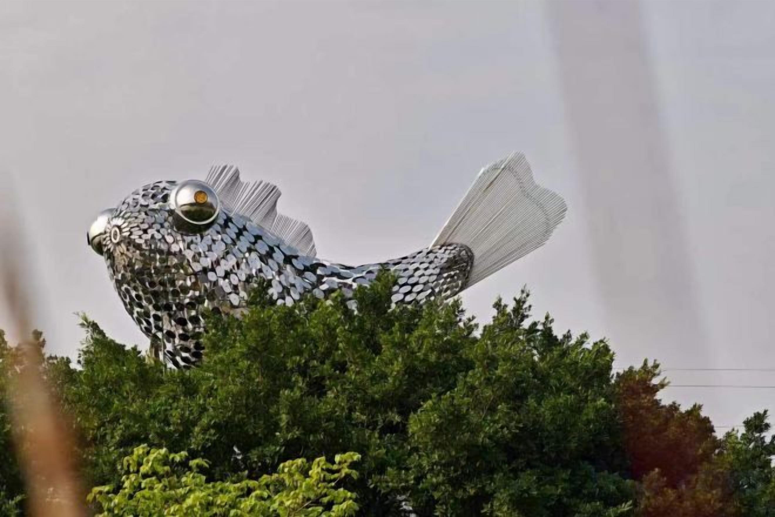 A large fish sculpture amidst greenery.