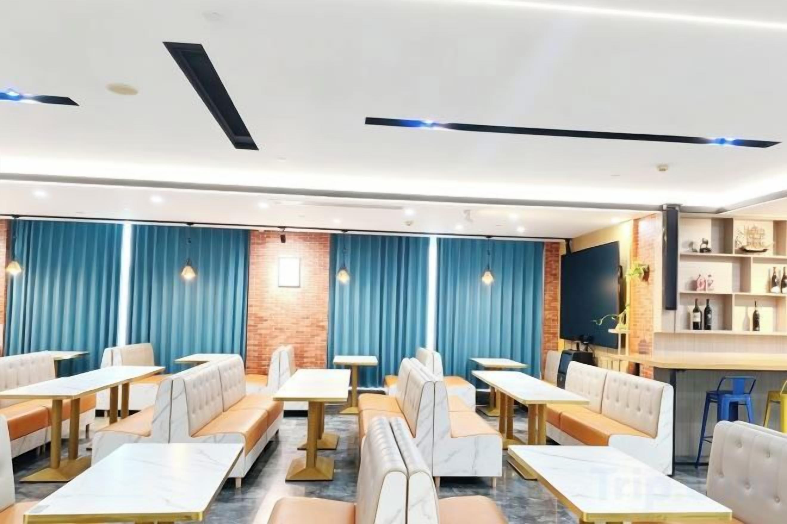 Un interno ristorante moderno con banconi e tavoli, tende blu, una parete decorata in mattoni e una zona bar.
