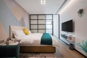 Ein modernes Hotelzimmer mit einem Bett, einem Fernseher, einem Schreibtisch und einer Pflanze.