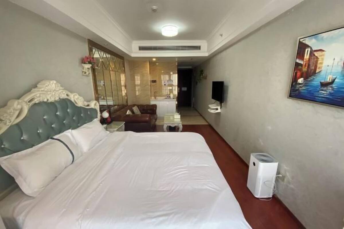 Een hotelkamer met een groot bed, een bank, een schilderij en een televisie.