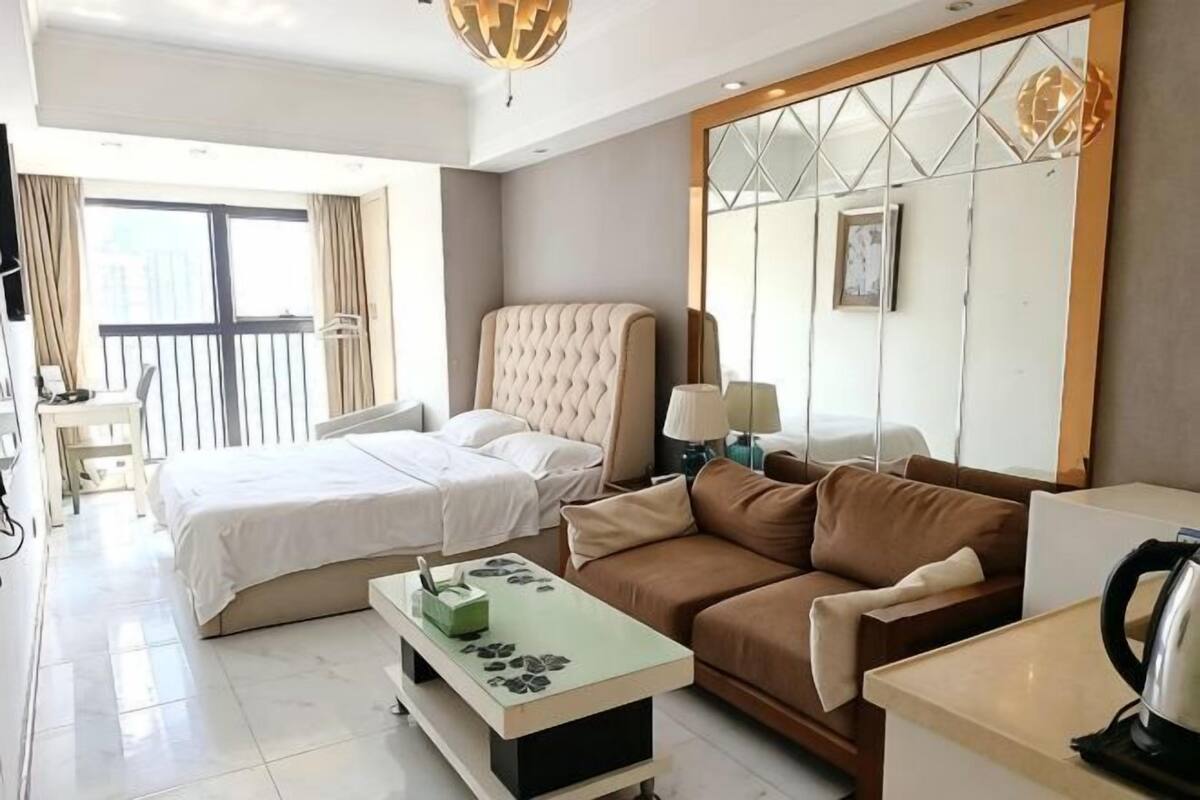 Een hotelkamer met een bed, een slaapbank, een bijzettafeltje, een televisie en een balkon.