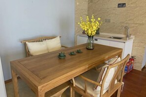 Ein Holzesstzimmer mit Stühlen, einer Vase mit gelben Blumen, einer kleinen Küchenzeile mit Spüle und einem Feuerlöscher.