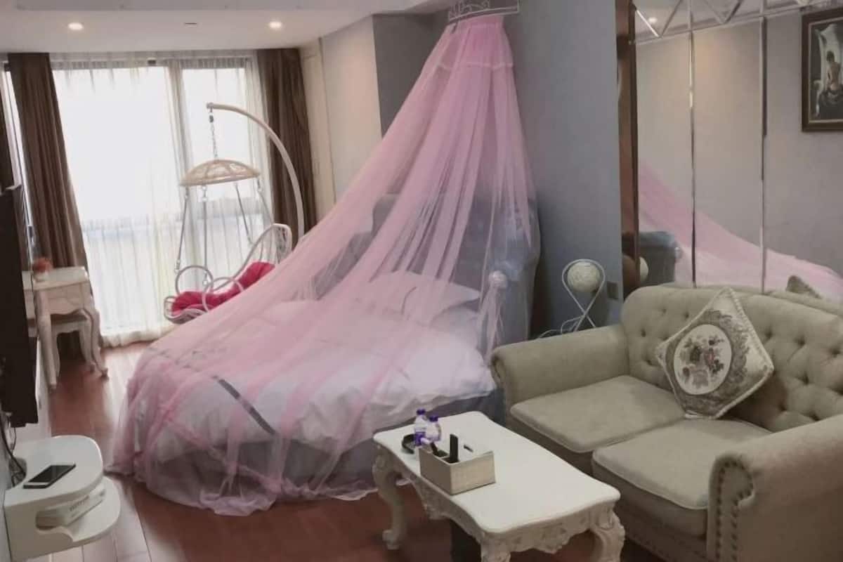 Een kamer met een bed, een hangstoel, een bank, een kleine tafel en een spiegel.