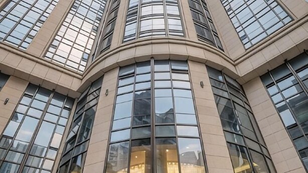 Un coin d’un bâtiment doté de grandes fenêtres et d’une façade incurvée.