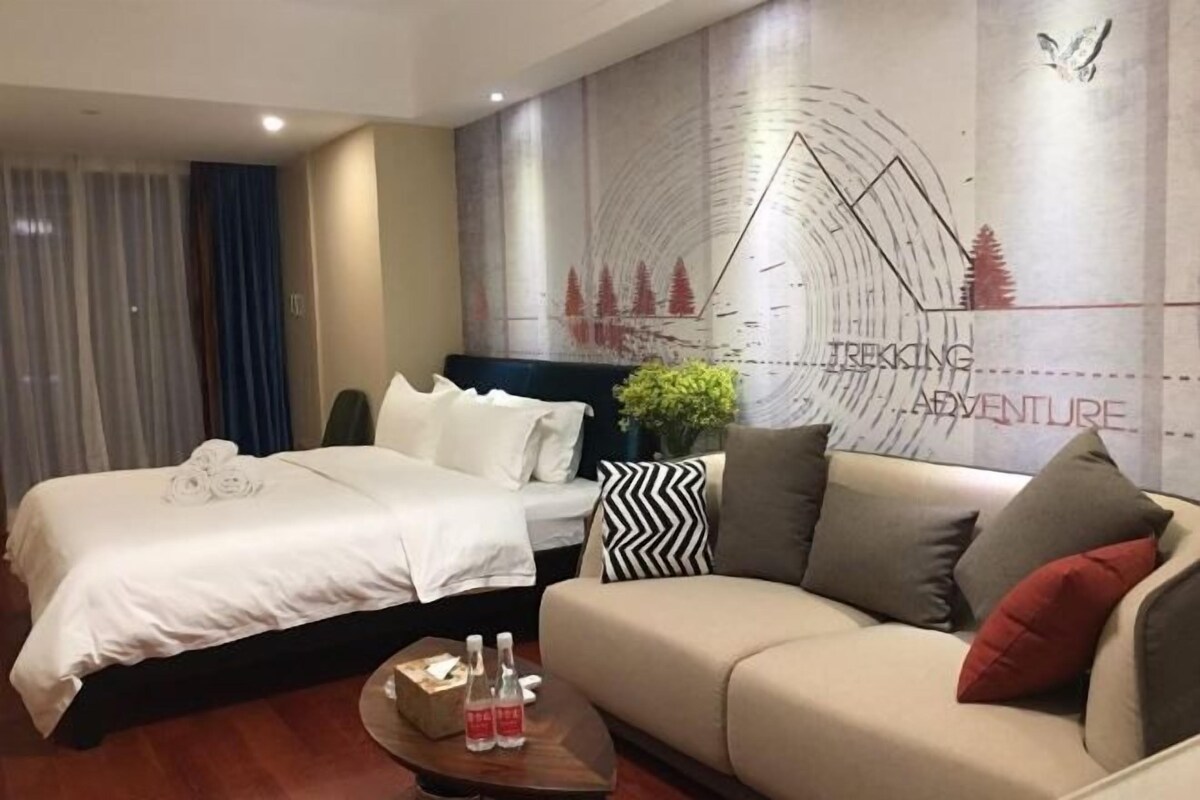 Een hotelkamer met een bed, een sofa, een koffietafel en een muur met een kaart en tekst.