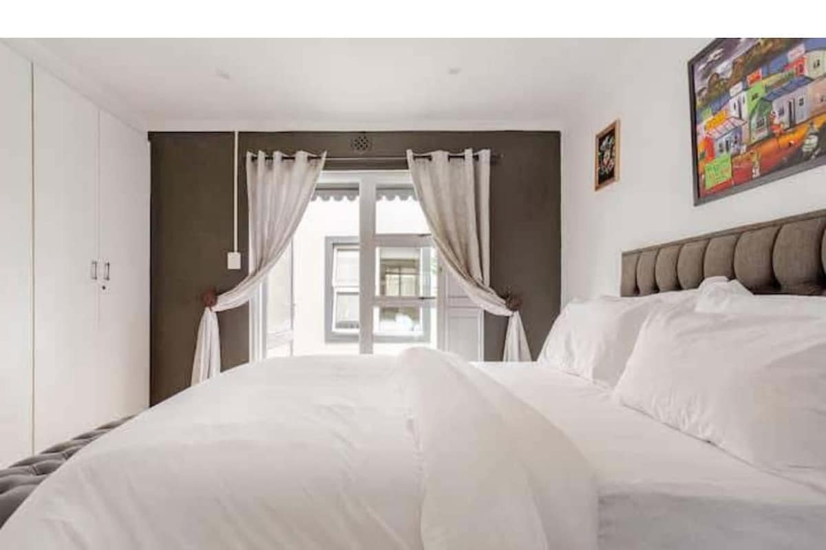 Ein Schlafzimmer mit einem Bett, Vorhängen, einem Fenster und einem Gemälde an der Wand.