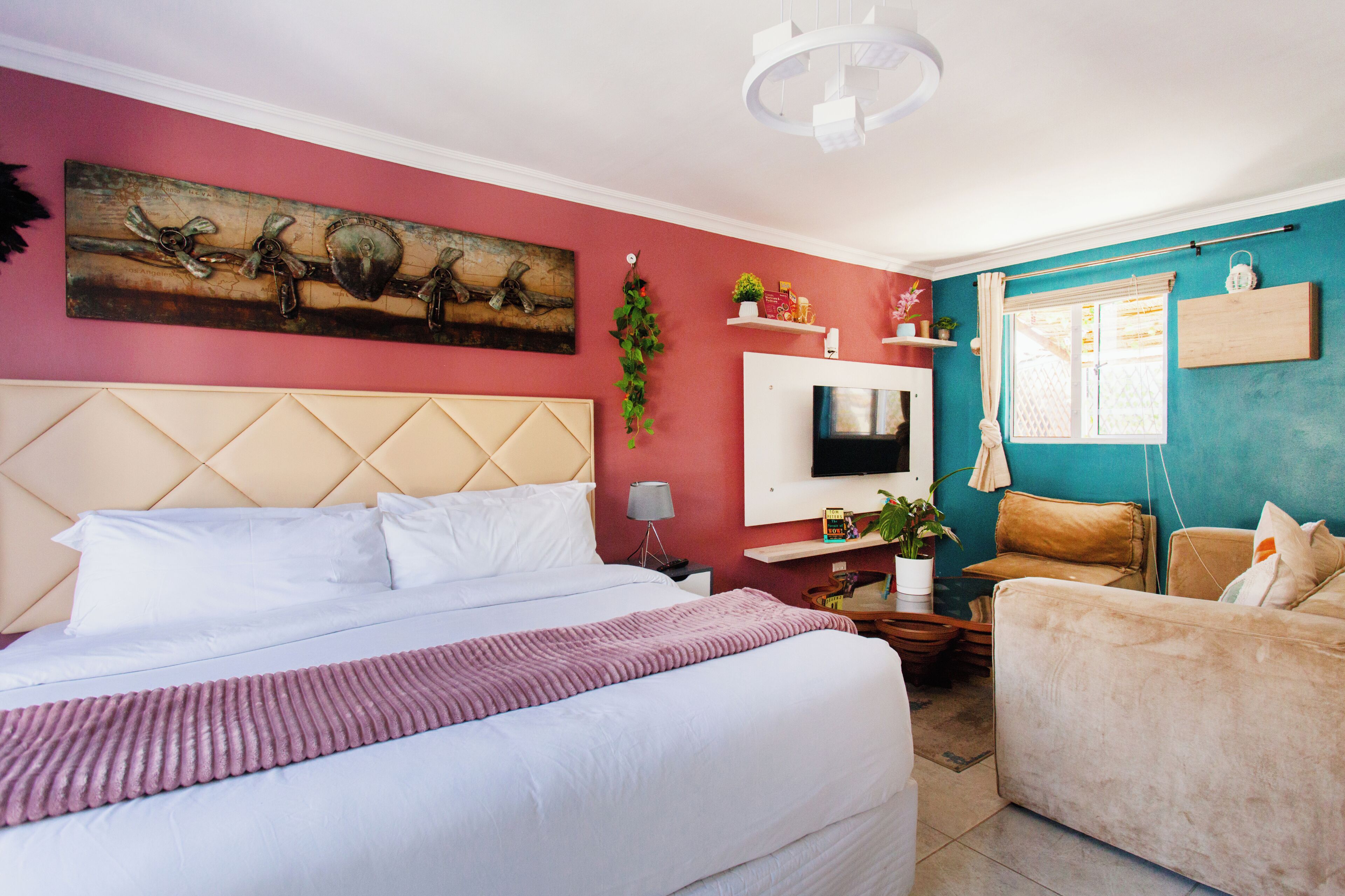 A hotel room with a large bed, a sofa, a TV, and a window with curtains.