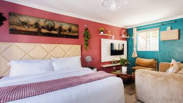 A hotel room with a large bed, a sofa, a TV, and a window with curtains.