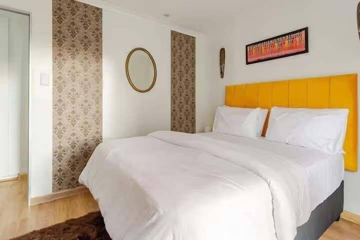 A bedroom with a bed, a mirror, and a painting on the wall.