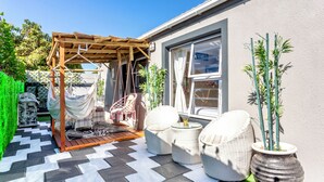 A patio with a wooden pergola, wicker furniture, and potted plants. - Caline VIP Mews (Cape Town)